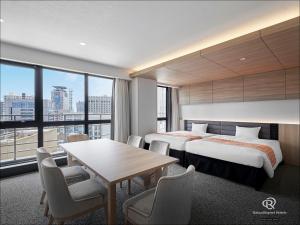 Cette chambre d'hôtel comprend deux lits, une table et des chaises. dans l'établissement Daiwa Roynet Hotel KOBE-SANNOMIYA PREMIER, à Kobe