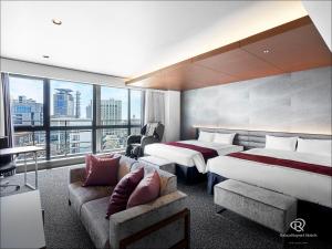 神戸市にあるダイワロイネットホテル神戸三宮PREMIERのベッド2台とソファが備わるホテルルームです。