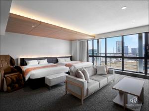 神戸市にあるダイワロイネットホテル神戸三宮PREMIERのベッドとソファ付きのホテルルーム