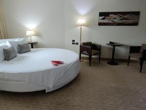 une chambre d'hôtel avec un grand lit blanc et des chaises dans l'établissement Green Hotel Ninfa, à Avigliana