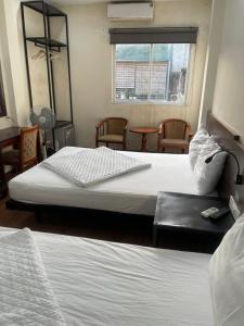 two beds in a room with chairs and a window at YÊN HÒA MOTEL in Hanoi