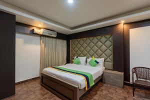 a bedroom with a large bed and a chair at Treebo Trend Kings Orchid in Bangalore