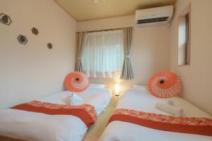 a bedroom with two beds with orange decorations on them at 匯家•平和島ビル in Tokyo