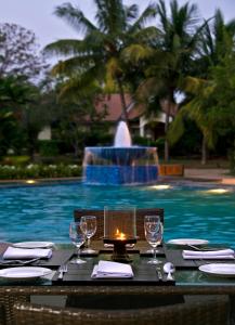 a table with wine glasses and a candle at a pool at The Golkonda Resort and Spa in Hyderabad