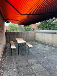 波塔韋斯特法利卡的住宿－Monteurzimmer，一张野餐桌和两把长凳,放在红伞下