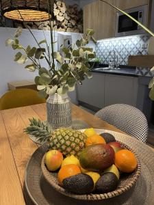 Olive & Ivy Guesthouse في Canillas de Aceituno: صحن فاكهة على طاولة مع مزهرية