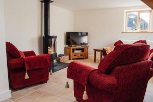 a living room with two red chairs and a fireplace at 'The Dairy' - Nestled in a traditional farmyard. in Stourbridge