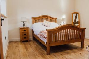 a bedroom with a wooden bed and a mirror at 'The Dairy' - Nestled in a traditional farmyard. in Stourbridge