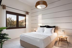 a white bedroom with a bed and a window at Aniv Villa by the Sea in Kinion