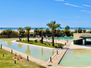 uma vista para uma piscina com palmeiras e para o oceano em OCEAN HOMES Apartamentos exclusivos en Isla Canela by AC REAL em Isla Canela