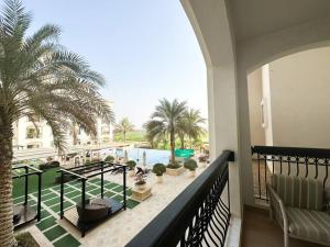 a balcony with a view of a pool and palm trees at On-The-Go Golf 202B3 in Abu Dhabi