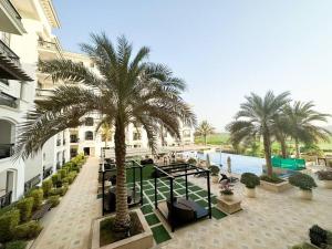 a building with palm trees next to a body of water at On-The-Go Golf 202B3 in Abu Dhabi