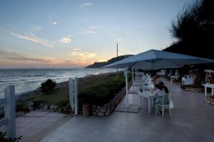 a woman sitting at a table under an umbrella on the beach at Dimora del Leone Gaeta in Gaeta