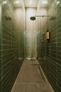a bathroom with a shower with green tiled walls at Hotel De Hallen in Amsterdam