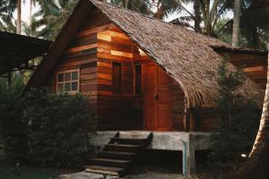 Cabaña de madera pequeña con techo de paja en Coco Camping Koh Kood, en Ban Khlong Chao