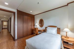 een slaapkamer met een wit bed en houten kasten bij Garden View Court Suites Ho Chi Minh City in Ho Chi Minh-stad