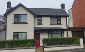 ein Haus mit einer roten Tür auf einer Straße in der Unterkunft Ballymena/ Belfast/ Antrim Coast/Galgorm in Ballymena