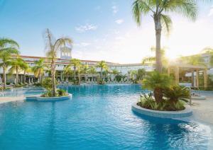 a swimming pool with palm trees in front of a building at Olympic Lagoon Resort Paphos in Paphos City