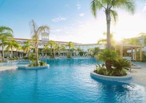 een zwembad met palmbomen voor een gebouw bij Olympic Lagoon Resort Paphos in Paphos City