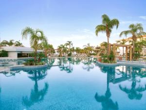 uma piscina com palmeiras num resort em Olympic Lagoon Resort Paphos em Pafos