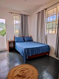 a bedroom with a blue bed and two windows at Port Louis Centre penthouse in Port Louis