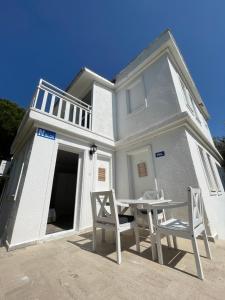 a white house with a table and chairs in front of it at Sun Beach Villas in Foca