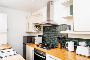 a kitchen with white cabinets and a stove top oven at Alice's Central Stay: Parking + Close to the Motor Point Arena in Nottingham