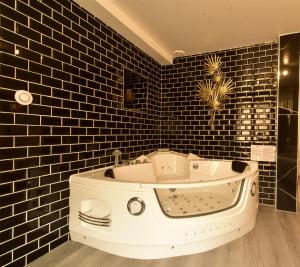 La salle de bains est pourvue d'une baignoire et de carrelage noir. dans l'établissement Appartement jacuzzi Gold&Night, à Verneuil-sur-Avre