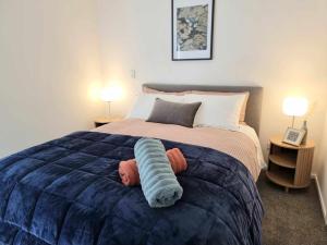 a bedroom with a bed with a blue comforter at CBD 3 Bedroom Apartment in Christchurch