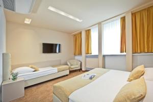 a hotel room with two beds and a tv at Hotel Central in Zagreb