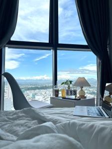 een bed met een laptop voor een raam bij Sunrise & Sunset Apartment View Marina Suites in Nha Trang