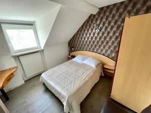 a small bedroom with a bed and a window at Hotel Restaurant Les Arcades in Valenciennes
