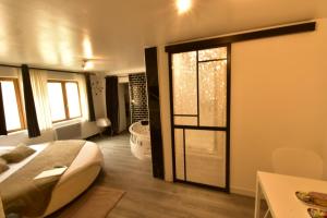 a bedroom with a bed and a bathroom with a tub at Appartement jacuzzi Gold&Night in Verneuil d'Avre et d'Iton