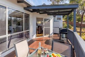 a deck with a table and chairs on a house at Sapphire Sunrise in Merimbula