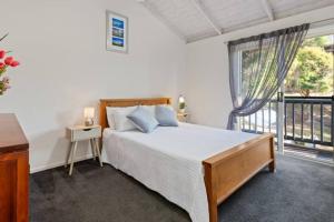 a bedroom with a bed and a large window at Sapphire Sunrise in Merimbula