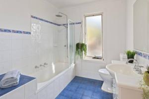 a bathroom with a tub and a toilet and a sink at Sapphire Sunrise in Merimbula