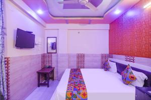 a bedroom with a bed and a flat screen tv at FabExpress Kanha Dham in Kānpur