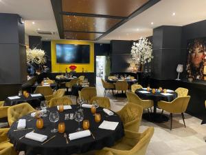 ヴァランシエンヌにあるHotel Restaurant Les Arcadesのテーブルと椅子、大画面のレストランを併設しています。