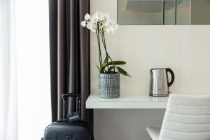 una valigia seduta su un tavolo con un vaso con fiori bianchi di Baldinini Hotel a Rimini