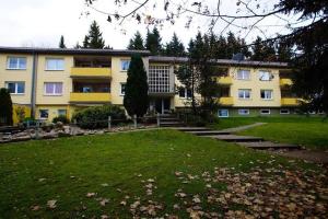 ein großes gelbes Gebäude mit einem Rasenplatz davor in der Unterkunft Ferienwohnung Mattejiet in Sankt Andreasberg