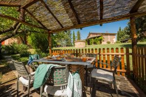 un patio con mesa y sillas bajo una pérgola de madera en Agriturismo Canale en Peccioli