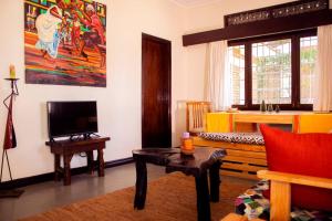 sala de estar con TV, sofá y mesa en Charming 2 bedroom house en Entebbe