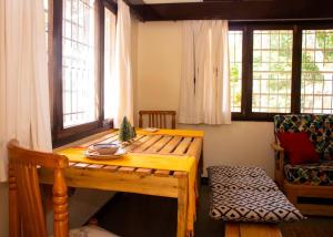 a wooden table and chair in a room with windows at Charming 2 bedroom house in Entebbe