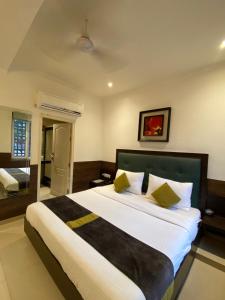a bedroom with a large bed with white sheets and yellow pillows at status business hotel in Kānpur