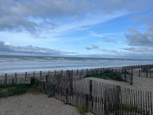 a fence on a beach with the ocean at Studio cosy au calme à 5 min de la plage in Camiers