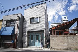 un edificio de ladrillo con una puerta azul en una calle en Nakamichi IKANIKAN - Vacation STAY 12151, en Osaka