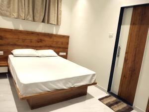 a bedroom with a bed with a wooden headboard at Hotel Majestic in Ulhasnagar