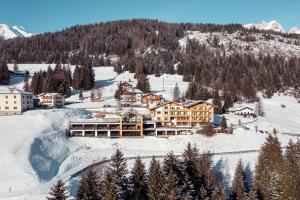 eine Luftansicht eines Resorts im Schnee in der Unterkunft Latemar - Hotel Suites Spa in Soraga