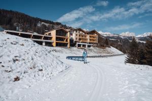 a person on skis in the snow in front of a lodge at Latemar - Hotel Suites Spa in Soraga