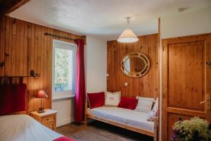 Schlafzimmer mit Holzwänden und einer Bank am Fenster in der Unterkunft LES PRIMEVERES in Saint-Jean-Saint-Nicolas